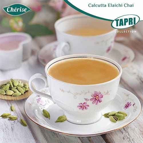 Calcutta Elaichi chai premix served in floral china cup with cardamom pods on wooden table